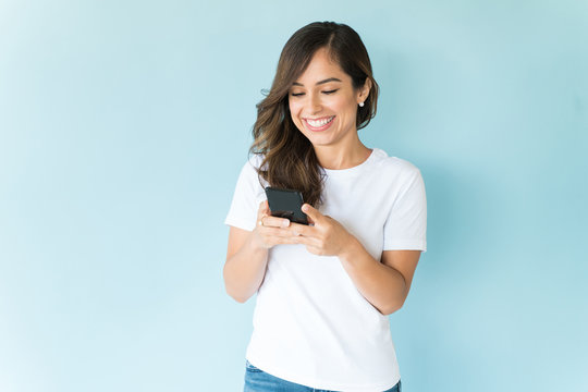 Smiling Woman Using Mobile Phone On Colored Background