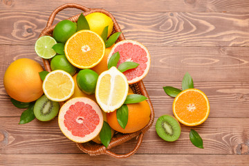 Basket with different fresh fruits on wooden background
