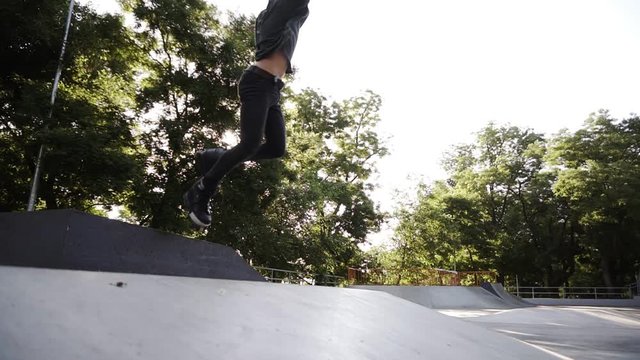 Man inline roller blader performing jumps at local skate park, Young gut on roller skates perform tricks on the ramp, freeze on the top then turn back and slide down. Extreme sports outdoors. Low