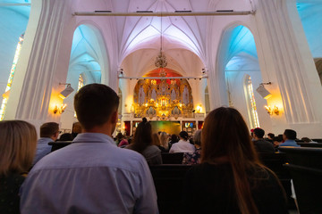 Organ music concert in cathedral. Men, women and other listeners listen to music of composer....