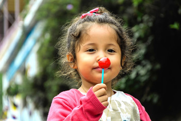 Portrait of cute girl with lollipop smiling in the park