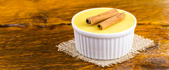 Obraz na płótnie Canvas Brazilian sweet cream-like dessert cured corn mousse with cinnamon on a rustic wooden background.