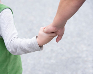 Ein Kind hält die Hand einer erwachsenen Frau