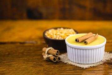 Typical Brazilian dessert, sweet of mingua, called in Brazil of curau. Typical sweet of June party. Brazilian sweet corn, corn mousse on a wooden background with copy space.
