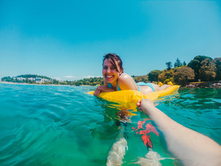 woman on yellow inflatable mattress in water man hand holding it point of view