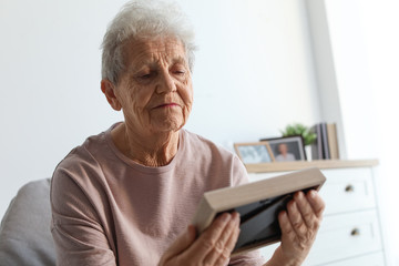 Elderly woman with framed photo at home