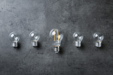 Vintage and modern lamp bulbs on grey stone surface, top view