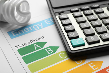 Energy efficiency rating chart, fluorescent light bulb and calculator, closeup