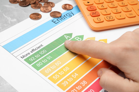 Woman with energy efficiency rating chart at table, closeup