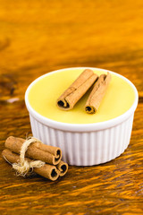 Brazilian sweet cream-like dessert cured corn mousse with cinnamon on a rustic wooden background. Typical Brazilian cuisine sweet in traditional parties, on a wooden background with copy space.