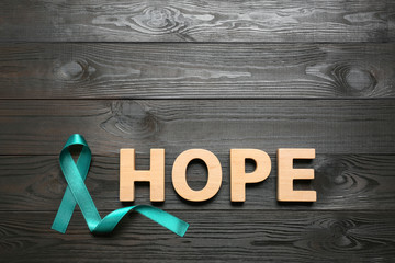 Word Hope made of letters and teal awareness ribbon on wooden background, top view. Symbol of...