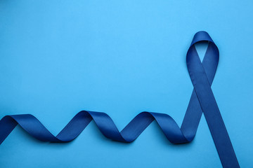 Blue awareness ribbon on color background, top view with space for text. Symbol of social and medical issues