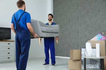 Young workers carrying sofa in room. Moving service