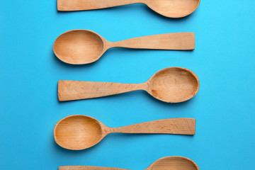 Clean empty wooden spoons on blue background, flat lay