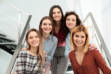 Portrait of happy ladies on stairs indoors. Women power concept