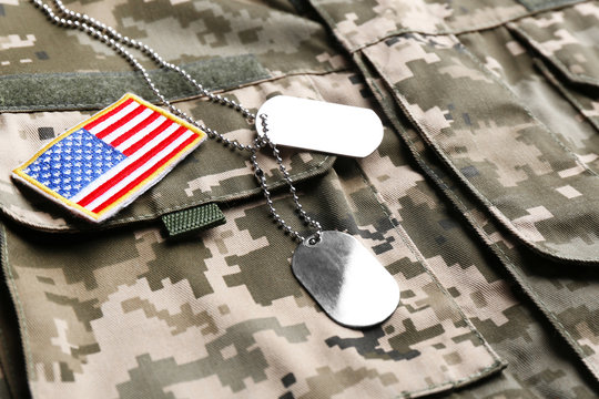 Military ID tags and US army flag patch on camouflage uniform