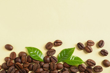 Fresh green coffee leaves and beans on light yellow background, flat lay. Space for text