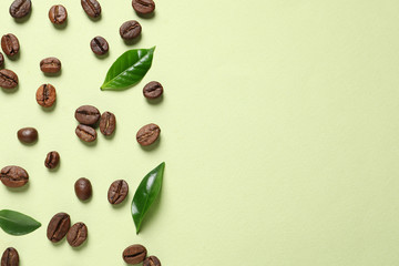 Fresh green coffee leaves and beans on light green background, flat lay. Space for text