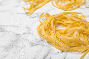 Raw egg noodles on marble table, closeup with space for text