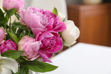 Bouquet of beautiful peonies on table in room, closeup. Space for text