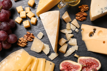 Composition with different types of delicious cheese and snacks on slate board, above view