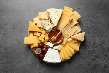 Different types of delicious cheese and snacks served on grey table, top view