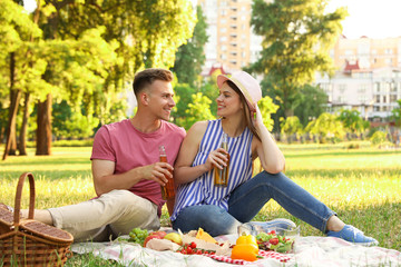 Young couple enjoying picnic in park on summer day