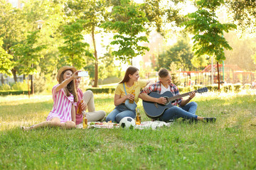 Fototapeta na wymiar Young people enjoying picnic in park on summer day