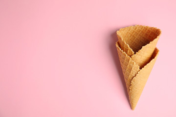 Empty wafer ice cream cones on pink background, flat lay. Space for text
