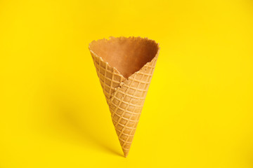 Empty wafer ice cream cone on yellow background