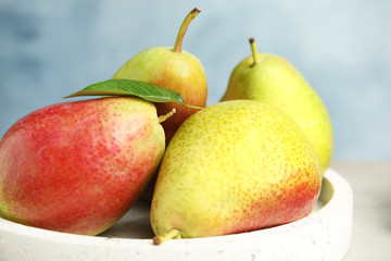 Plate with ripe juicy pears against blue background, closeup