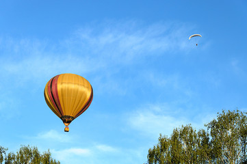 Colorful hot air balloon and paraglider over the blue sky.
