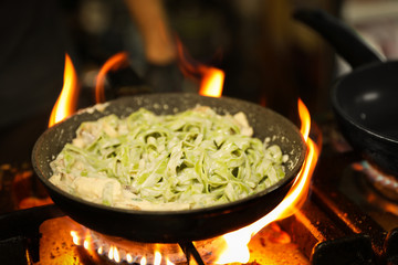 Cooking delicious noodles with melted cheese on frying pan