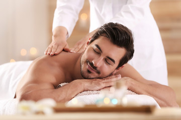 Handsome young man receiving back massage in spa salon
