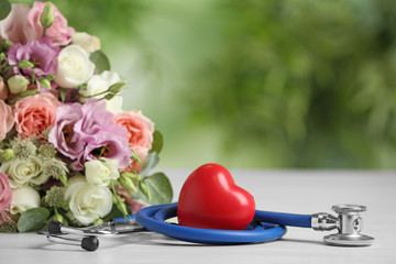 Composition with red heart and stethoscope on white table against blurred background. World health...