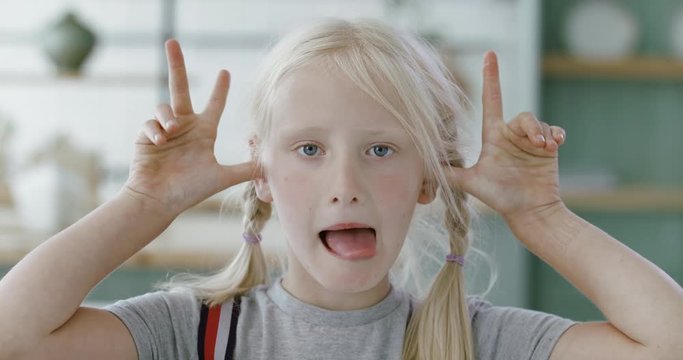 FIXED Portrait of little cute Caucasian girl doing silly funny face, looking into camera. 60 FPS Slow Motion, 4K RAW graded footage