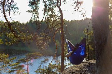 Moody sunset photo of a man in a hammock. Shallow depth of field and a low angle. © samuli