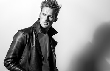 Handsome young man in classic leather jacket. Black-white studio portrait.