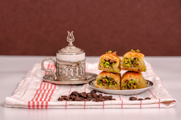 turkish delights - baklava with turkish coffee, coffee beans on the white fabric and brown background