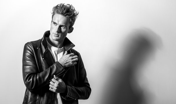 Handsome young man in classic leather jacket. Black-white studio portrait.