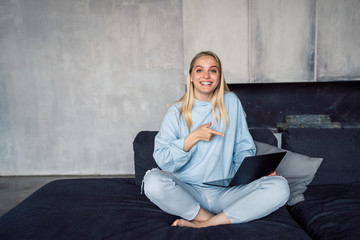 Image of happy woman using silver laptop while sitting on sofa