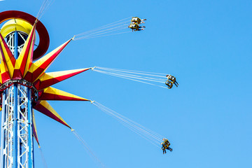 People in amusement park on carousel, high in the blue clear sky. Happy entertainment concept....
