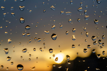 Rain outside window on background of sunset. Rain drops on glass during rain. Bright texture of...