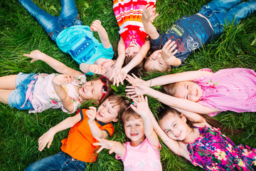 A group of children lying on the green grass in the Park. The interaction of the children.