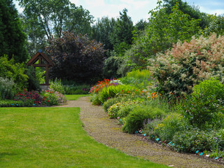 Beautiful garden in summer with green lawns, paths and mixed flower borders, North Yorkshire,...