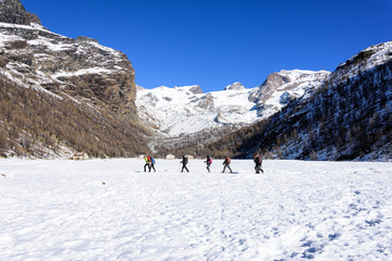 Group of hikers trekking in the mountains of the Alps. The trekkers are going through a snowy landscape