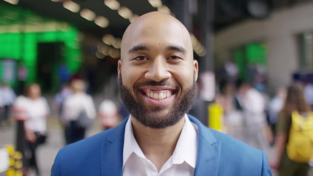 Portrait of handsome business man smiling to camera in the middle of rush hour, in slow motion