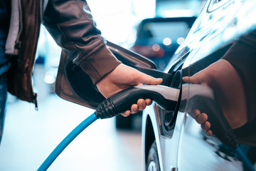 Human hand is holding Electric Car Charging connect to Electric car - 282732511