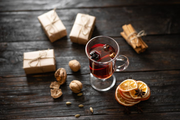 delicious and fragrant mulled wine on the table, anise, cinnamon and orange, Christmas gifts in craft paper