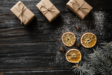 Fototapeta premium Christmas background with place for your text. Orange slices and gifts lie on a wooden table